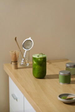 Refreshing matcha latte with ice in a glass on a wooden table