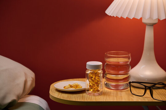 A bedside scene displays a lamp, glass, pills and lamp