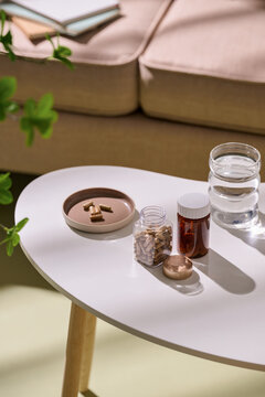 Supplements and water on a table and a cozy sofa in the background
