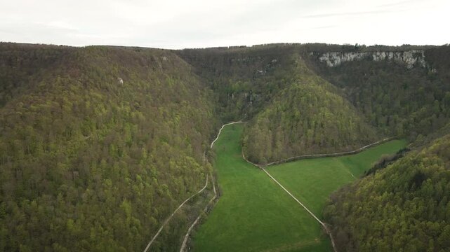 Smooth 4K UHD drone push-in flying forward into the Gro&szlig;e Lautertal (Lauter Valley) in the Swabian Alb, showcasing forested hills and vivid green meadows&mdash;ideal for travel films, ads.