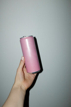 Hand holding bright pink mockup metal drinking can with space for text