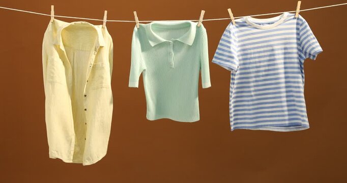 Different clothes drying while hanging on clothesline against brown background