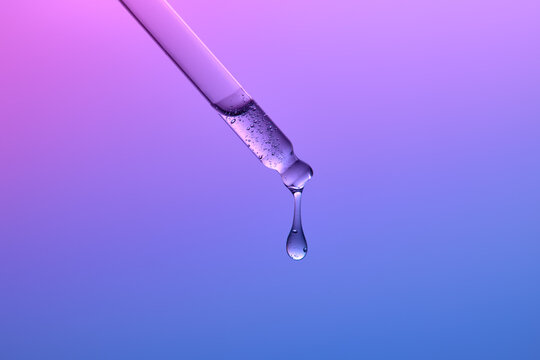Droplet of Liquid Falls From a Pipette on a Gradient Blue Background