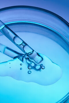 Petri dish with glass pipette and face serum on a gradient background.
