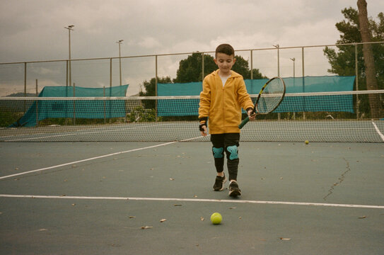 Boy Plays Tennis on a Court in Cloudy Weather