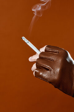 smoke rising from a cigarette held by a man wearing a leather glove