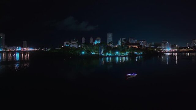 Aerial night view of the city of Recife, Pernambuco, Brazil, highlighting the illuminated urban center and the Pal&aacute;cio do Campo das Princesas along the river. 