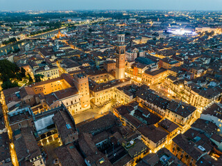 Night view of Piazza delle Erbe with the Torre dei Lamberti illuminated above the square. Historic buildings, warm lights, and lively atmosphere define Verona most iconic public space after dark