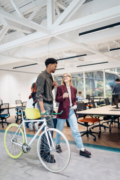 Colleagues walking and talking in modern office with bicycle
