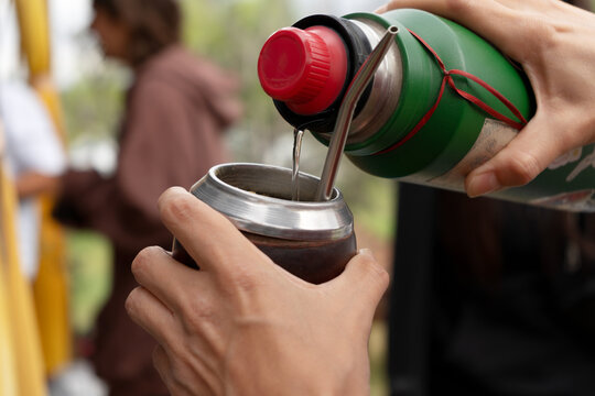 Close-up of hand preparing mate with thermos
