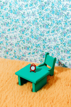 a small green table with a red alarm clock resting on top