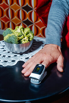 at home, a man monitors his oxygen levels with a pulse oximeter
