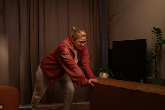 Woman unpacking television box in living room