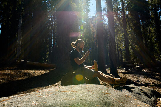 Man rests on a fallen tree trunk in the forest