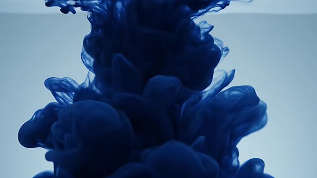 Dark blue ink cloud swirls and diffuses in clear liquid, creating ethereal patterns