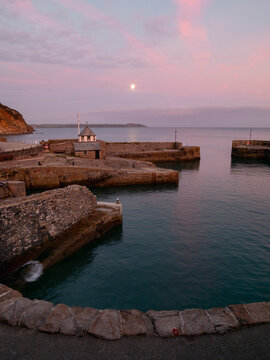 Harbour at dusk with calm sea, moon and pink sky