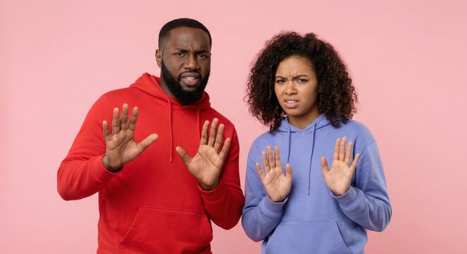 African American man and woman showing stop gesture with disgusted expression on pink background