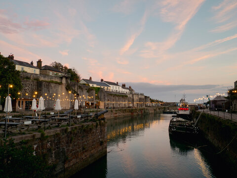 Evening sky over historic harbour with string lights at sunset