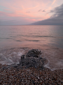 Sunset over calm sea with rocky shore