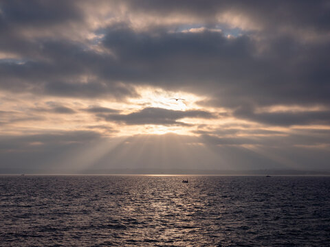 Sea at sunrise with sun rays over calm water