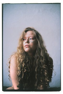 Woman with curly hair poses in studio with neutral background
