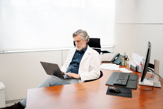 Senior doctor working on laptop in modern office
