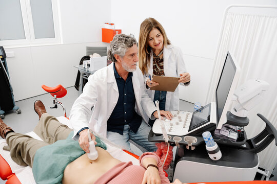 Gynecologist and doctor performing abdominal ultrasound on woman