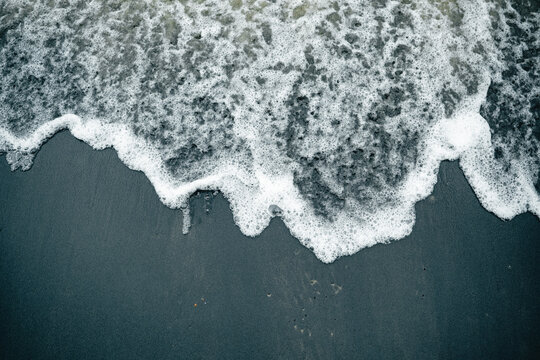 Foamy Ocean Wave on Dark Sand