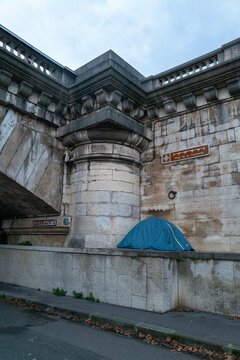 Tent Set up Under a Bridge in City Near Road and Signs