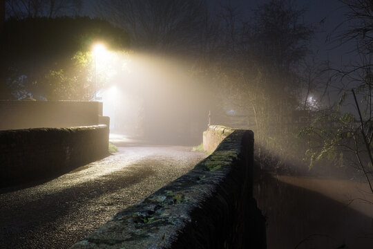 A historic bridge on a foggy winters night