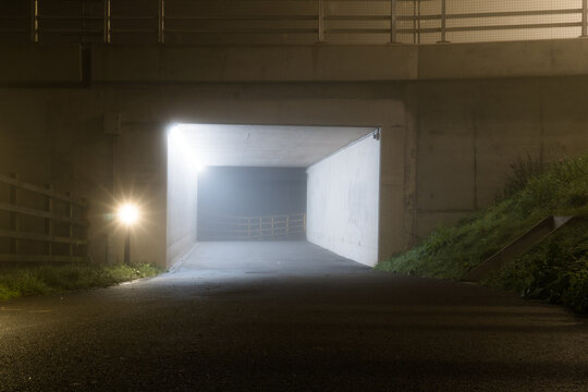 An underpass below a road on a foggy winters night