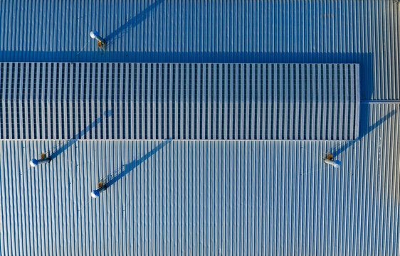 Top-Down View of Solar Panels on Blue Corrugated Roof

