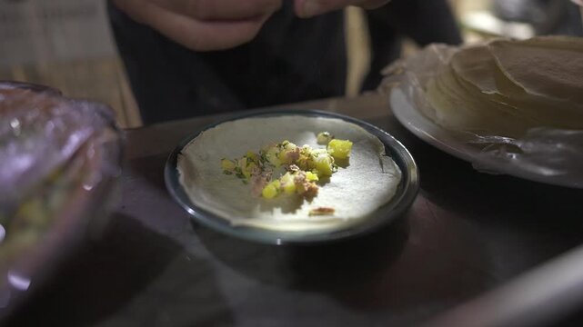 Hands cracking a fresh egg onto flatbread while preparing a simple homemade meal on a kitchen counter
