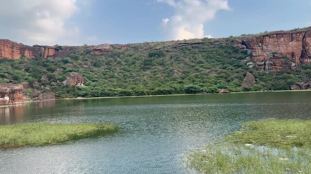 A panoramic view capturing the vast red sandstone mountain range, Agastya Lake, and the historic Bhoothnath Temple, highlighting the majestic and serene landscape of Badami