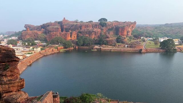 Beautiful aerial time-lapse of Agastya Lake with calm waters, framed by the majestic red sandstone mountain range, capturing the timeless beauty and serenity of Badami&rsquo;s historic landscape
