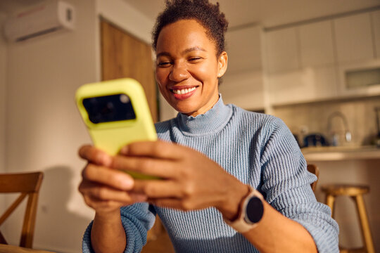 Happy woman stares at her phone in the kitchen