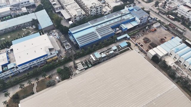 Drone footage over Greater Noida&rsquo;s industrial zone showing expansive factory roofs, logistics yards, and surrounding greenery, softened by atmospheric haze caused by urban and industrial air pollution