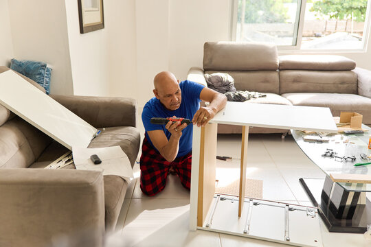 Man Builds Furniture in Living Room During Daylight Hours