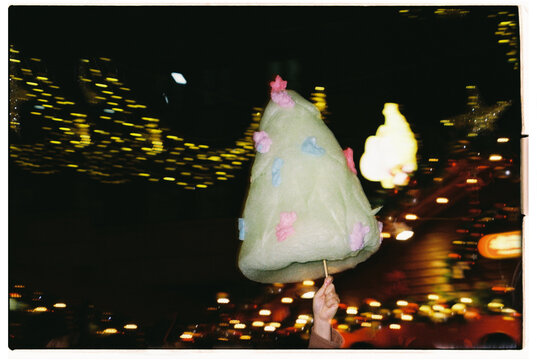 Cotton candy shaped like a Christmas tree held at a festive market