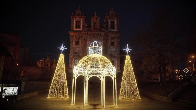 Christmas symbol light installation in front of a historic church at night.