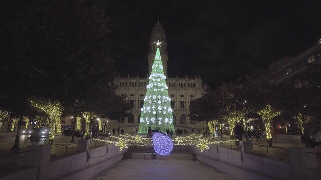 Large green Christmas tree in front of Porto City Hall at night.