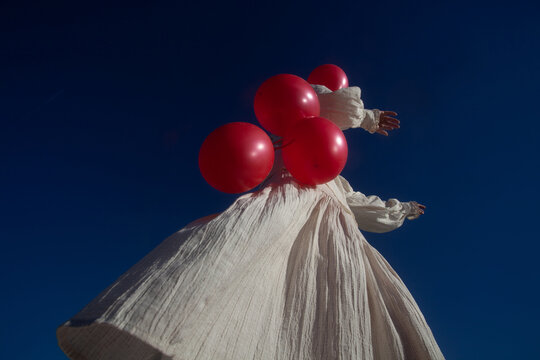 A woman in white with the red balloons 