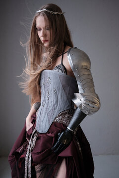 Young woman in armor with a prosthetic arm poses for a photo shoot