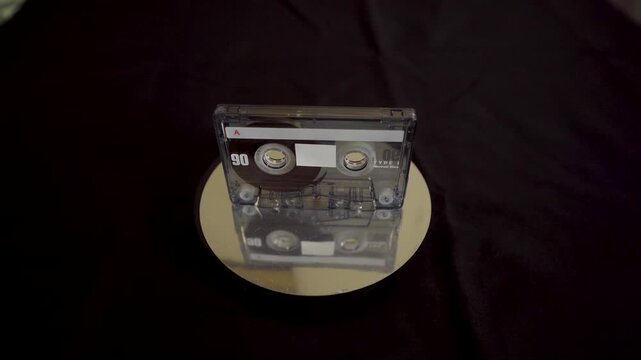 Single cassette tape standing upright on a reflective surface.
