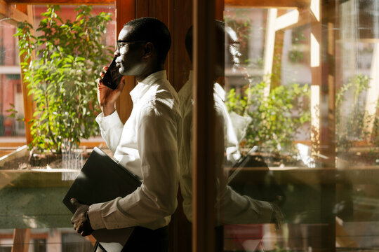 Businessman talking on phone in sunlit office