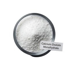 Calcium Oxalate Monohydrate powder in a glass container viewed from directly above on a plain white surface