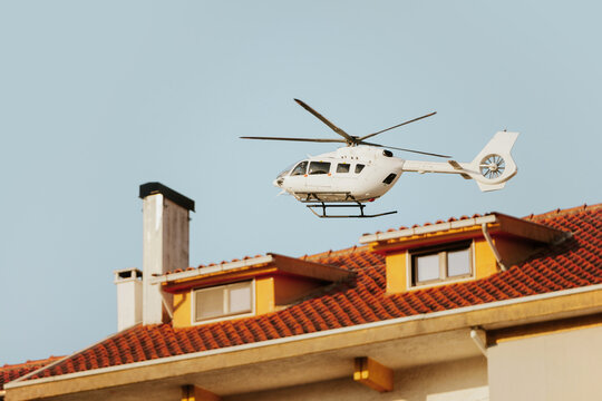 Helicopter flying above a house with orange roof tiles