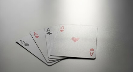 Obraz premium Close-up of four playing cards, all aces, with different suits, against a gray gradient