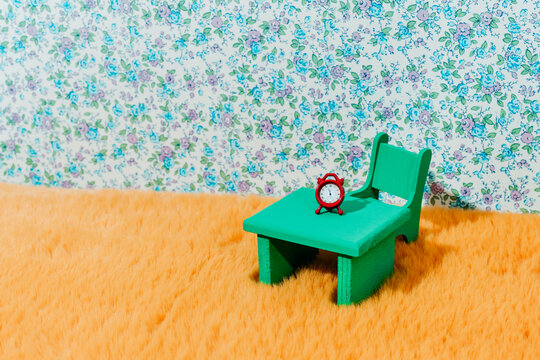 interior scene showing a red alarm clock on a green table