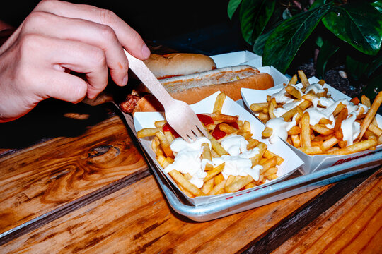 a man picking at fries topped with mayonnaise and ketchup